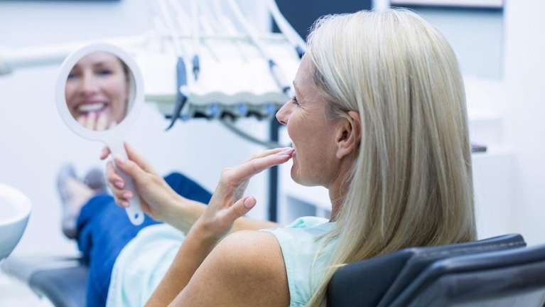 A woman checks her dental implant as she sits in a dental chair in Florida